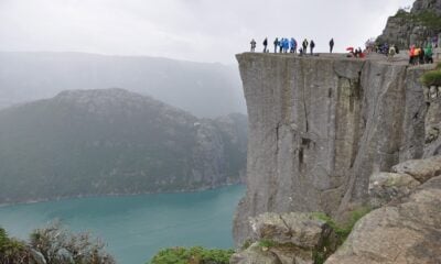 Hikers looking out from Preikestolen cliff, one of the most famous tourist sights in all of Norway.