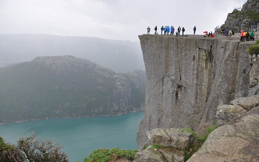 Hikers looking out from Preikestolen cliff, one of the most famous tourist sights in all of Norway.