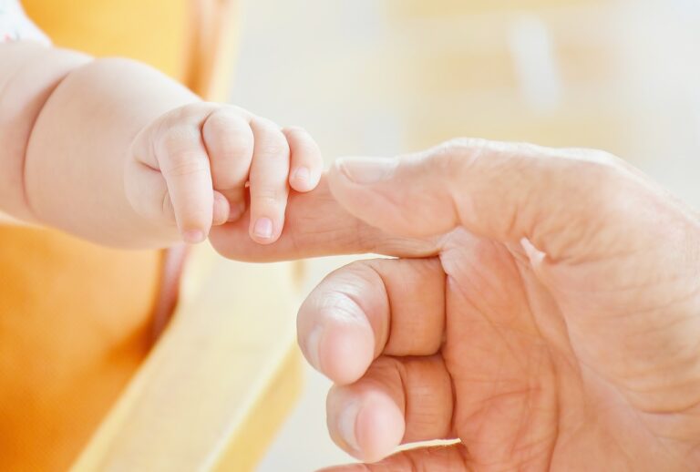 A Norwegian baby holding its parent's finger.