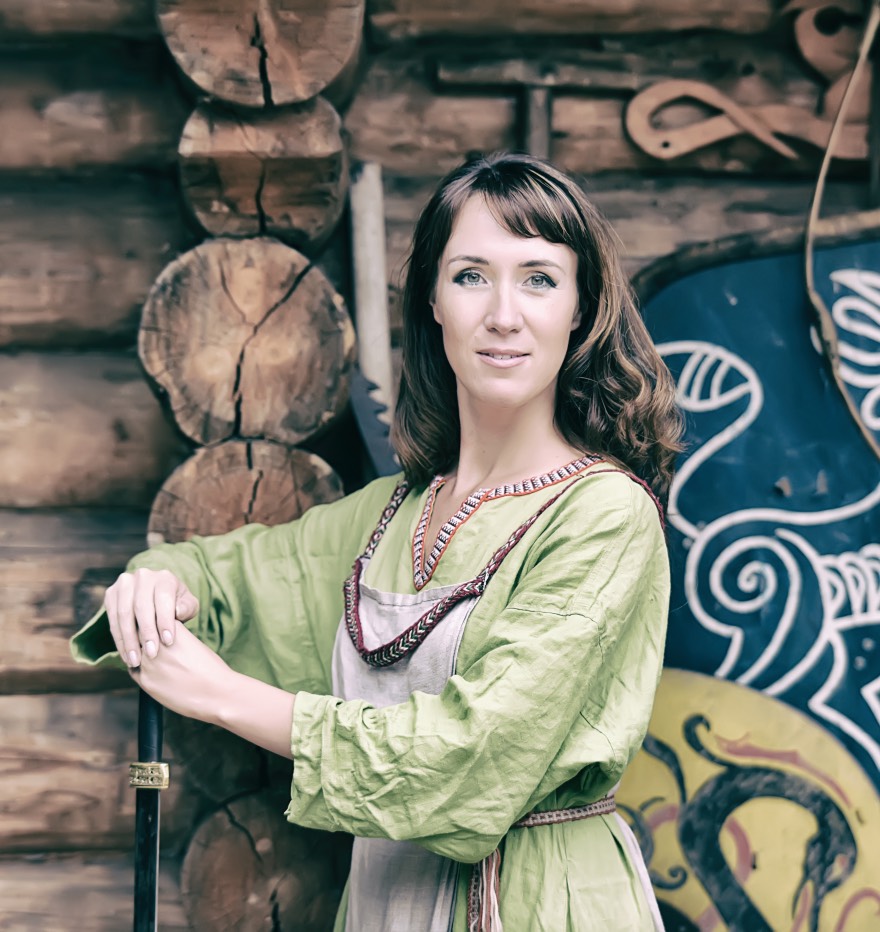 A woman dressed as a Viking in a green dress at a reenactment.