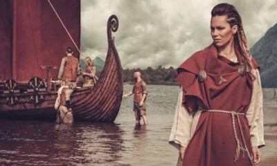 Viking woman standing near Drakkar on seashore
