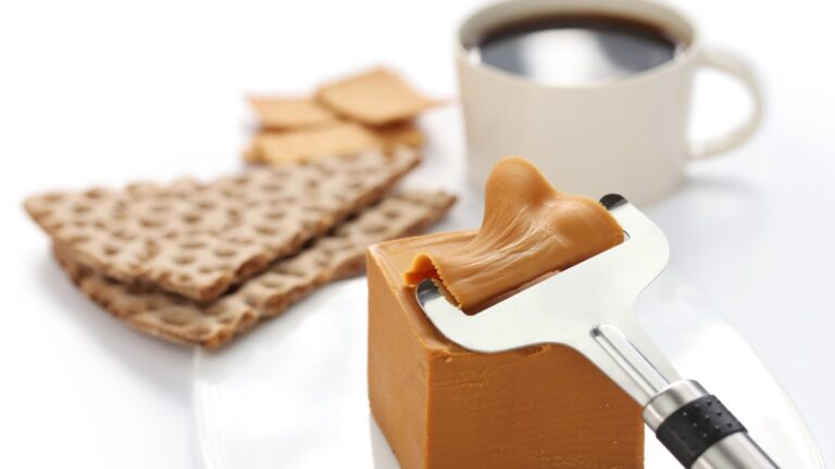 Block of Norwegian brown cheese and coffee at breakfast time.