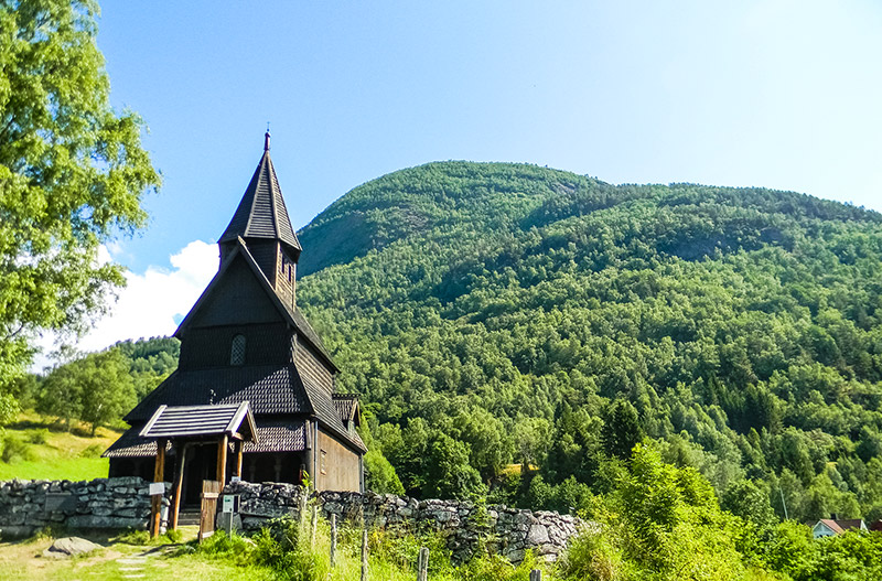 Urnes stave church in a green field in Norway