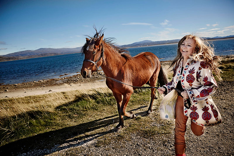 Mari Boine running with a horse on a beach