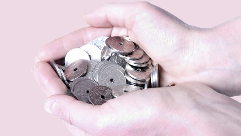 Hand holding coins from Norway.