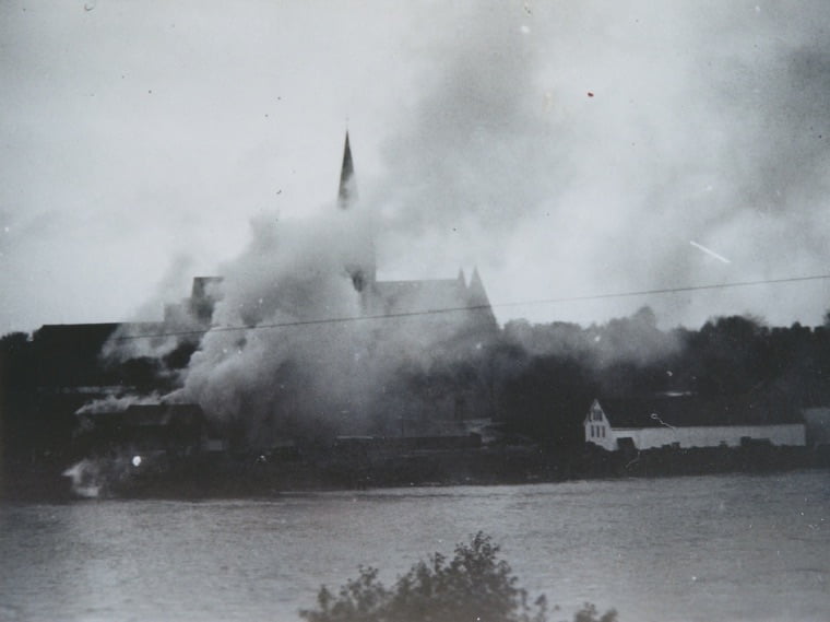 Nidaros Cathedral stands in the background as a wooden building burns in Trondheim, Norway