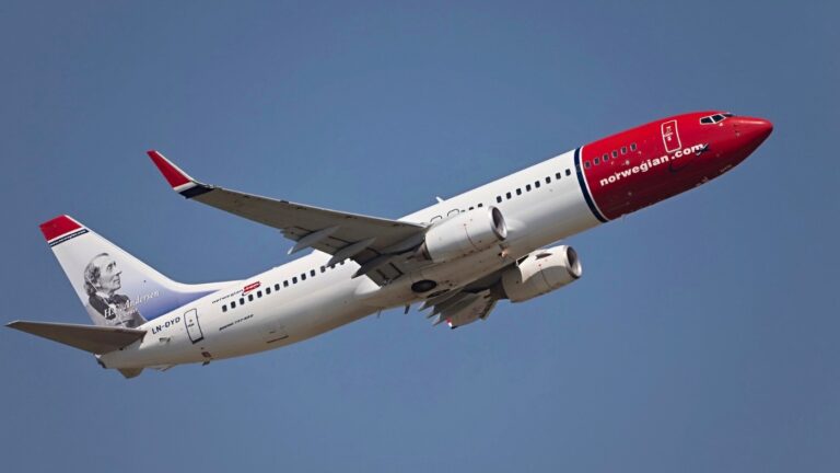 Norwegian Air plane in flight with Hans Christian Andersen depicted on the tail fin. Photo: Gudella / Depositphotos.com.