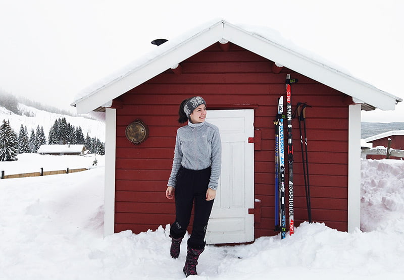 Mon Amie standing in front of a Norwegian cabin in the snow