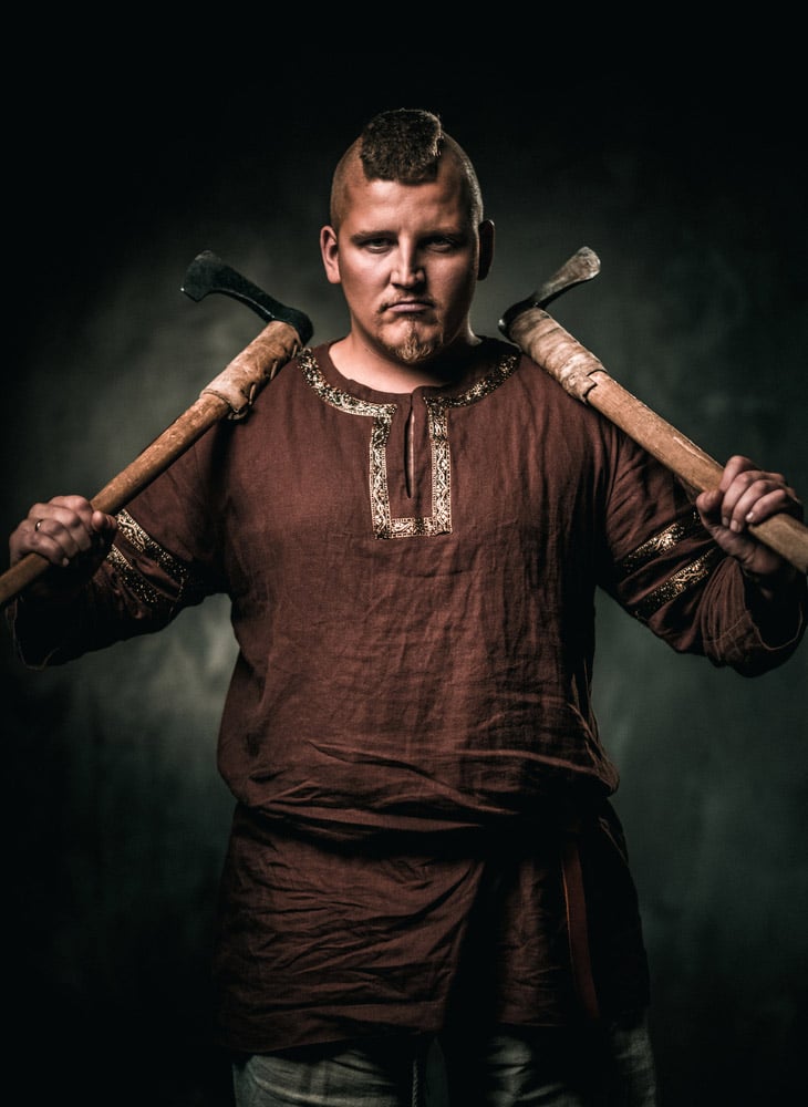 Guerrier viking dans des vêtements typiques tenant deux axes