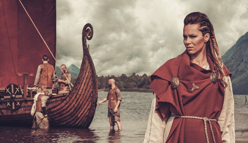 Viking woman standing by ship in the water