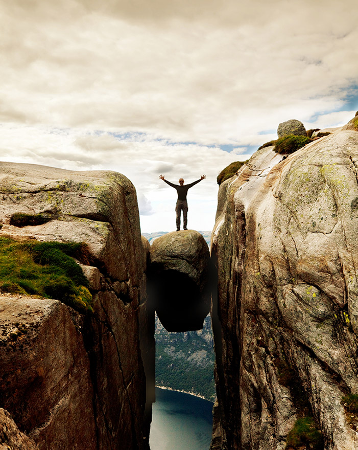 Hiker standing on Kjeragbolten in Norway