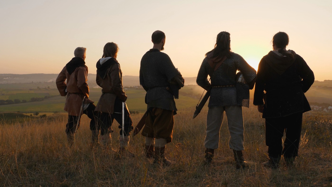 Viking men in a field at sunset.