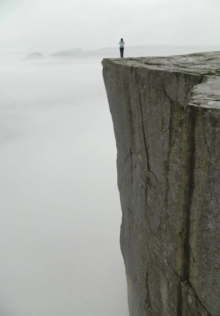 Norwegian standing on the Preikestolen cliff on a foggy day