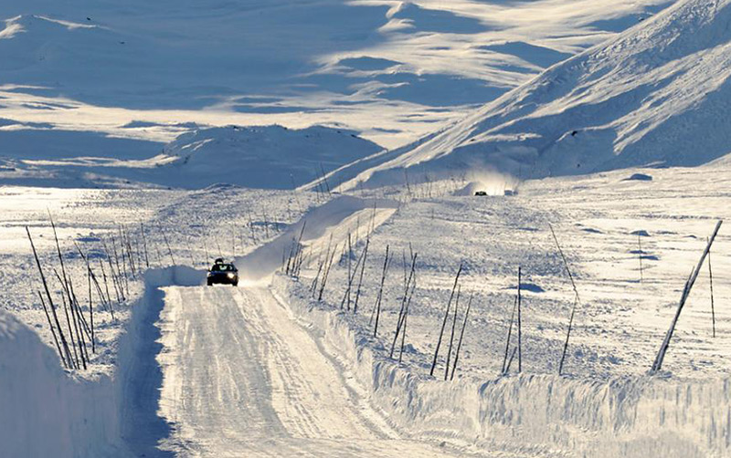 A car driving on the snow-covered Valdresflye mountain road in central Norway