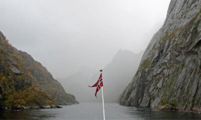 A boat with a Norwegian flag sailing into Norway's Trollfjord