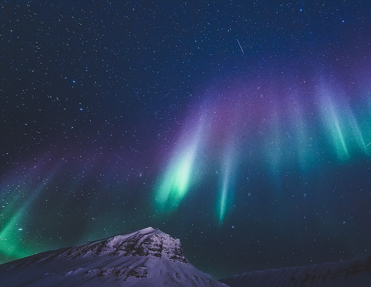 An aurora borealis display of green and purple lights above Longyearbyen, Svalbard