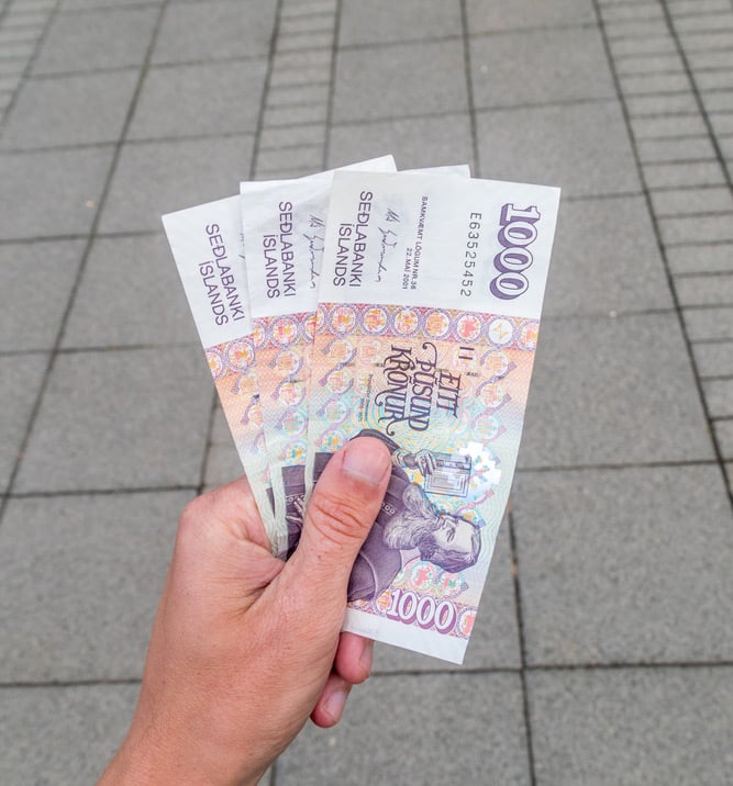 Icelandic krona banknotes clutched in a hand