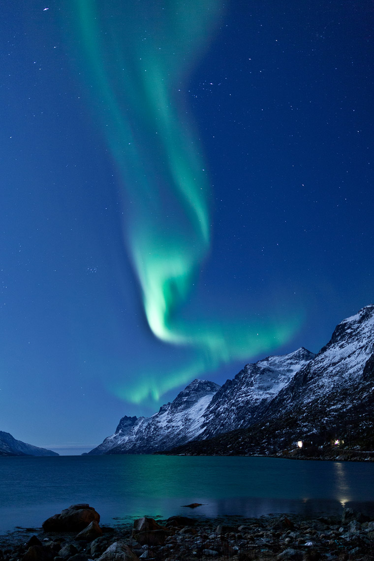 Green northern lights above a mountain in a Norwegian winter