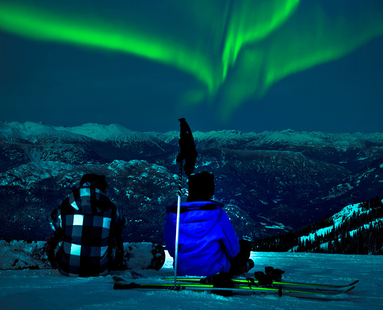 Skiers watching the aurora borealis in Northern Norway