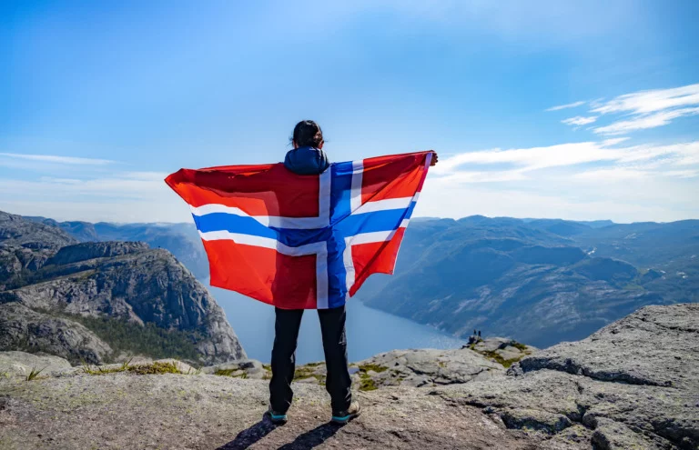 Hiker in the Norwegian mountains holding the flag of Norway