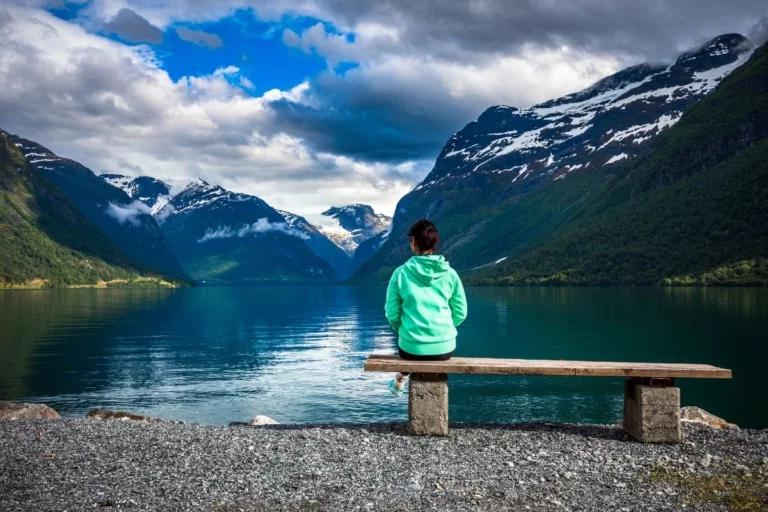 A hiker contemplating the peaceful lake Lovatnet in fjord Norway