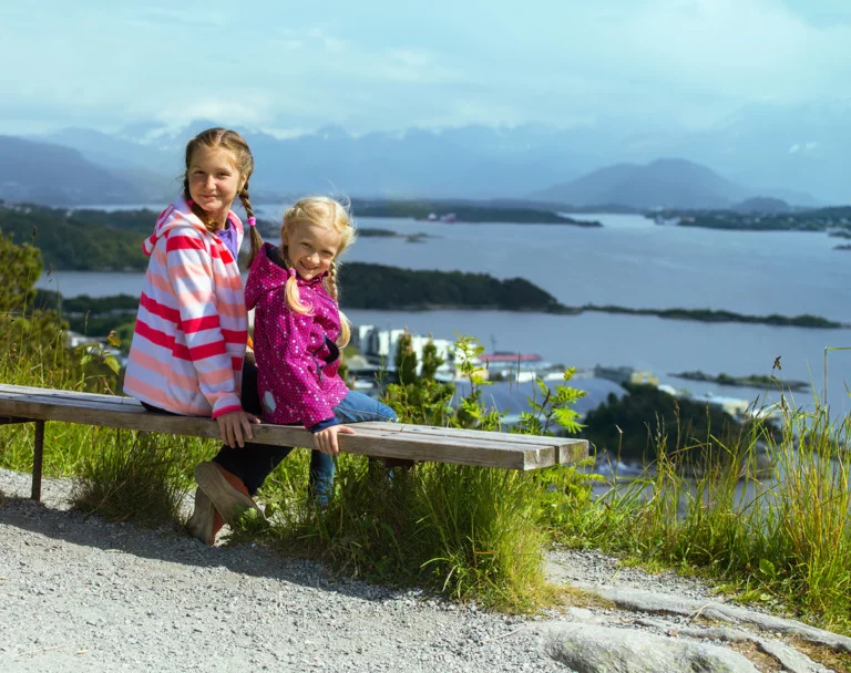 Norwegian children on a waterside bench.