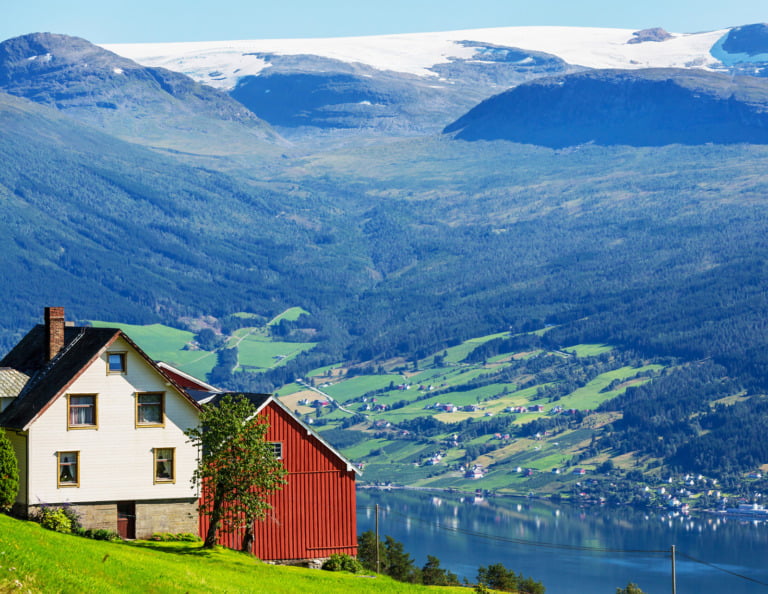 Rural Norwegian houses on a hillside overlooking a fjord.