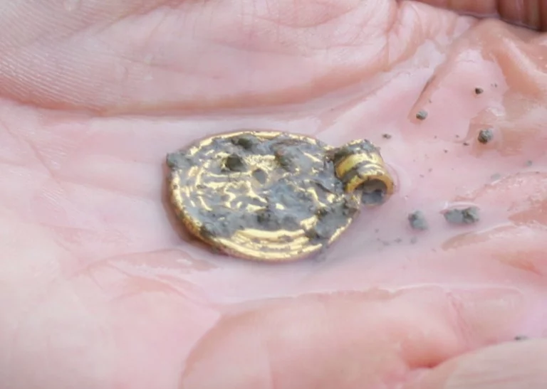 Recovered gold bracteate in a person's hand.