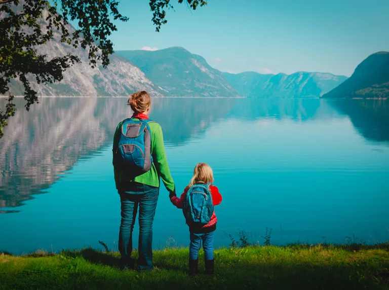 Mother and girl standing by a Norwegian fjord