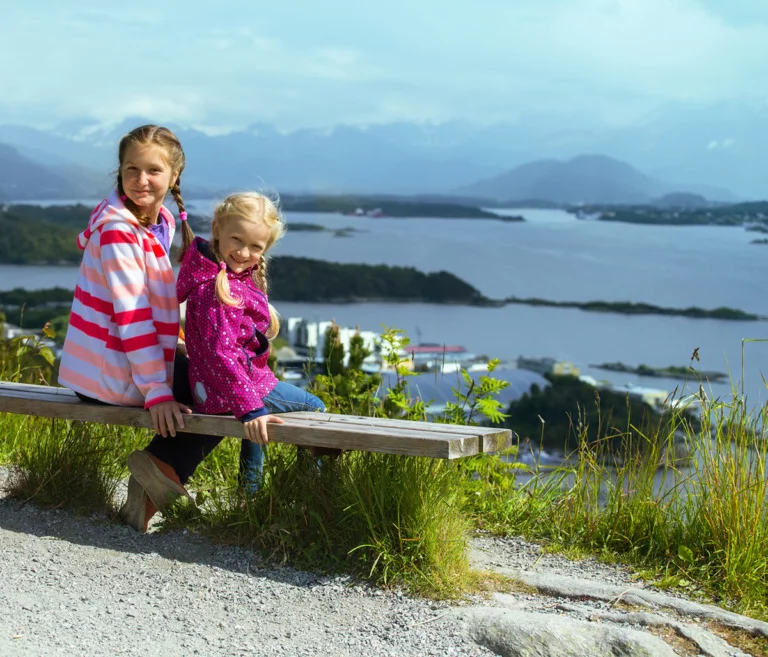 Two Norwegian girls sitting by a fjord in Norway
