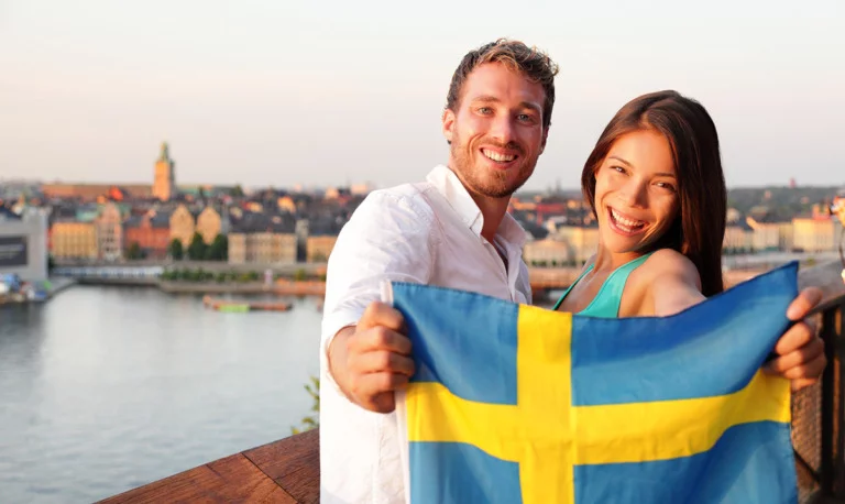 Two Swedish people holding the flag of Sweden