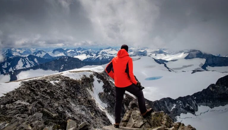 Hiker admiring the view from Galdhøpiggen mountain in Norway.