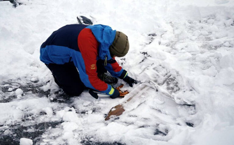 Julian Post-Melbye shovels away snow around the ski.