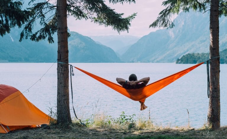 Man relaxing in a hammock on a Norwegian campsite.