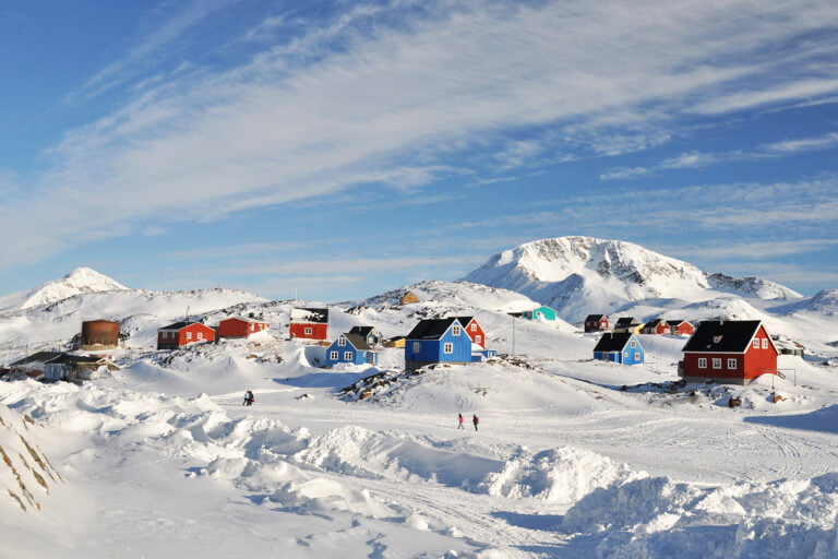 Colourful houses and people walking in Kulusuk village, Greenland.