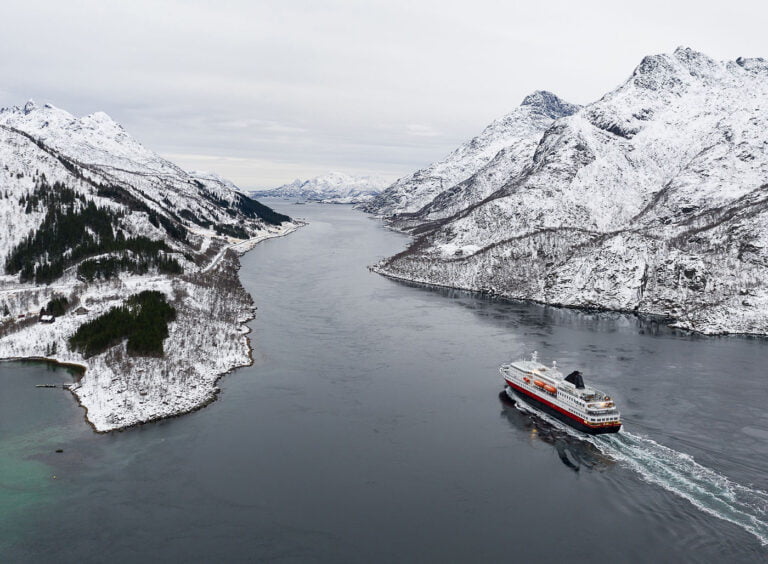 Hurtigruteferge i Norge går inn i en fjord om vinteren.