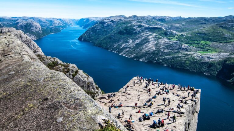 People on Norway's iconic Pulpit Rock hike with the Lysefjord in the background.