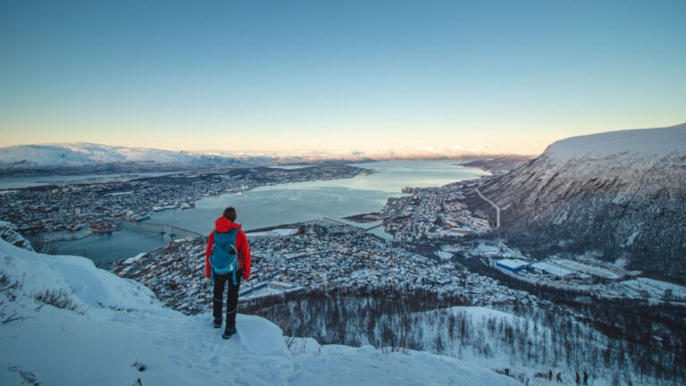 Hiker and a winter panorama of Tromsø, Norway.