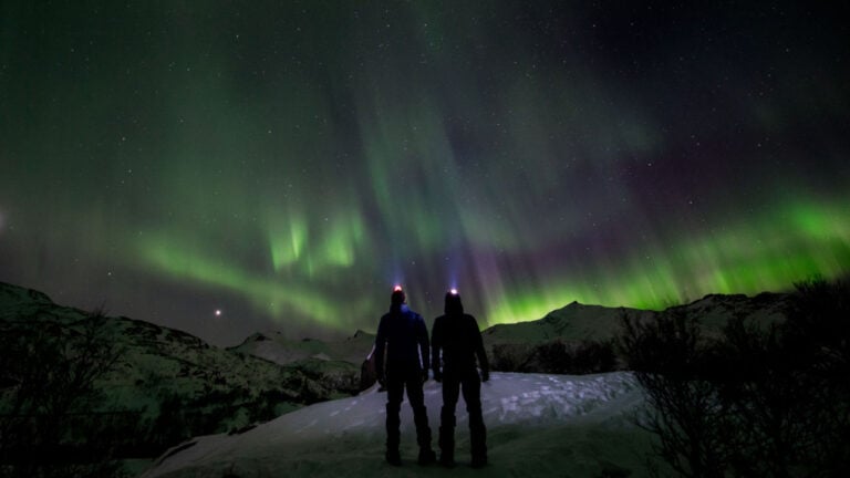 Two people watching the northern lights in Norway.