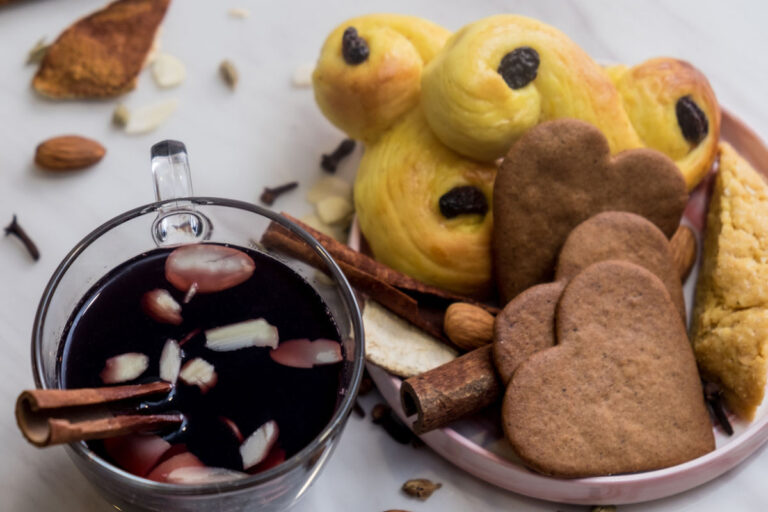 A glass of gløgg with gingerbread biscuits and saffron flavoured buns.