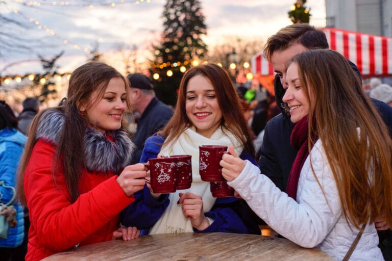 Three women enjoying mugs of gløgg at a Christmas market in Scandinavia.