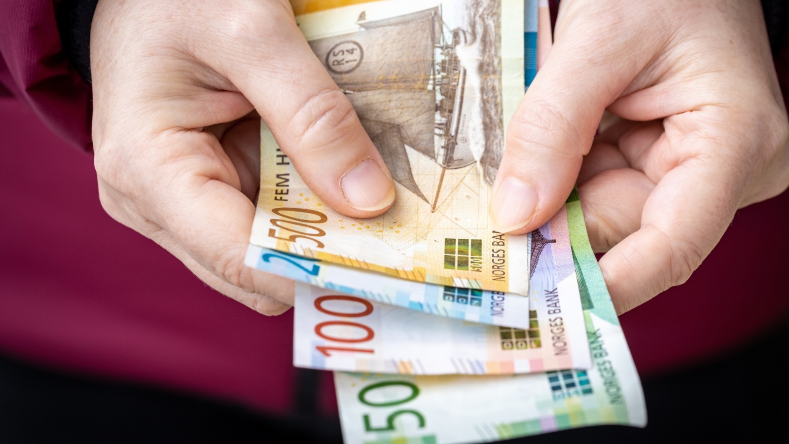 Hand holding Norwegian krone banknotes.