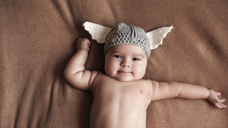 Norwegian baby boy wearing a crocheted viking helmet.