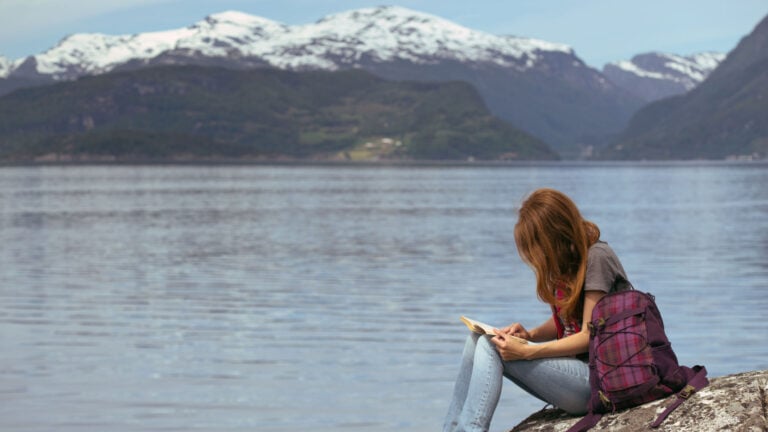 Girl reading a Scandinavian book by a fjord.
