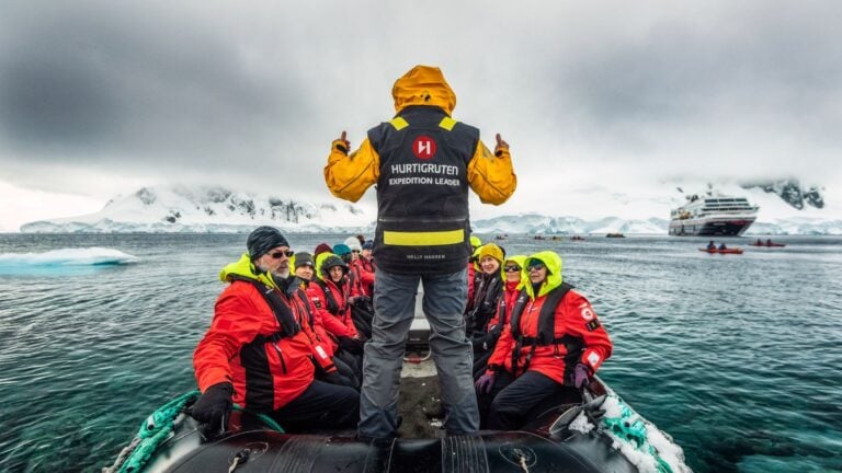Hurtigruten Expeditions team on a small craft with the MS Maud in the background. Photo: Karsten Bidstrup / Hurtigruten Expeditions.