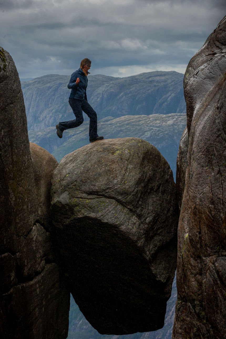 Person stepping out onto the Kjerag boulder in Norway.