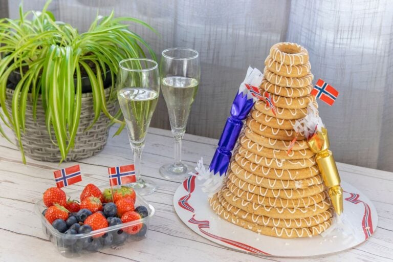 A decorated kransekake with wine and berries.