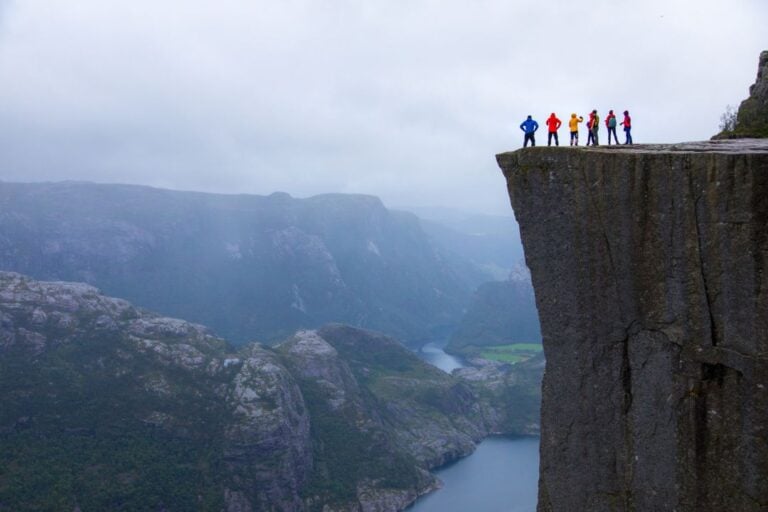 Hikers standing on top of Preikestolen rock in Norway.