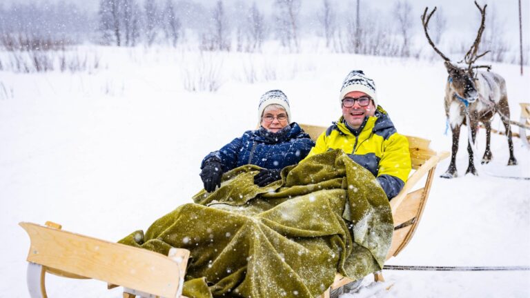 David and his mum on a reindeer sled in the snow.