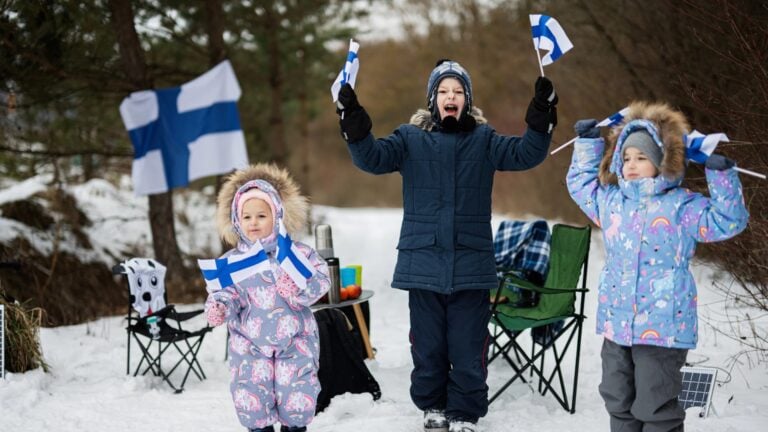 Finnish people waving flags of Finland in the snow.
